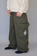 Person wearing green cargo pants with a logo on a plain background