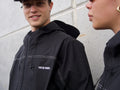 Person wearing a black jacket with 'Tweeide Boards' branding against a light-colored wall.